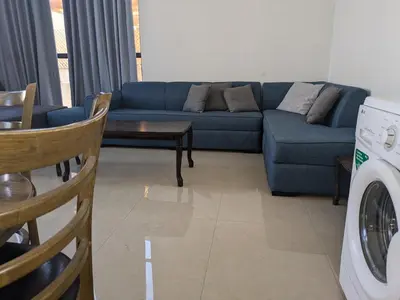 a living room with a blue couch and a washing machine at Aeropuerta Mini Villa - Private self check-in Layover near Airport in Al Qasţal