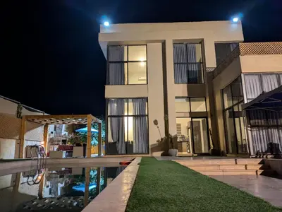 a building with a pool in front of it at night at Aeropuerta Mini Villa - Private self check-in Layover near Airport in Al Qasţal