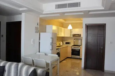 a kitchen with a white table and a white refrigerator at Cosy appartement in Umm Uthainah