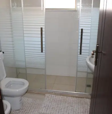 a bathroom with a shower and a toilet and a sink at Cosy appartement in Umm Uthainah