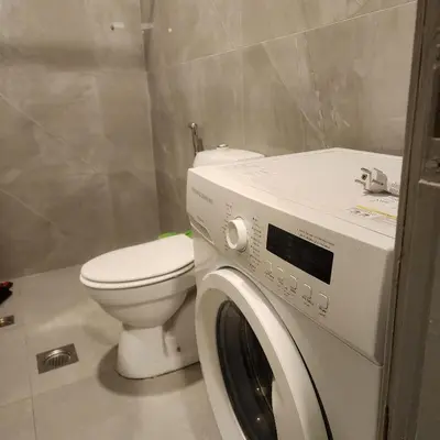 a bathroom with a toilet and a washing machine at Flat In Shafa Badran in Ţāb Kirā‘
