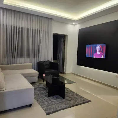 a living room with a couch and a tv on a wall at Flat In Shafa Badran in Ţāb Kirā‘