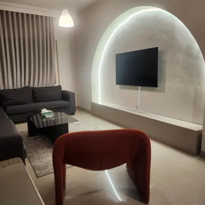 a living room with a couch and a tv on a wall at Flat In Shafa Badran in Ţāb Kirā‘
