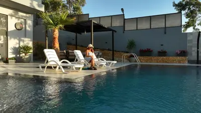 a woman sitting next to a swimming pool at شاليه بيت التل HILLHOUSE Chalet in Al Maşţabah