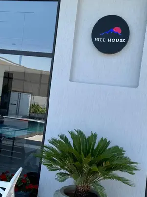 a sign on the side of a building with a palm tree at شاليه بيت التل HILLHOUSE Chalet in Al Maşţabah