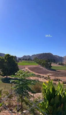 a field with a fence and trees and mountains at Country cottage in Al Ḩayy