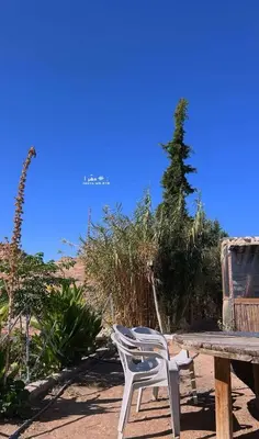 a white chair sitting next to a wooden table at Country cottage in Al Ḩayy