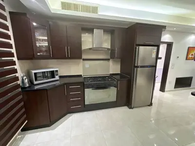 a kitchen with wooden cabinets and stainless steel appliances at 2 En-suite Rooms, Central & Spacious in Amman