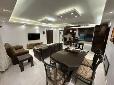a living room with a table and chairs and a television at 2 En-suite Rooms, Central & Spacious in Amman