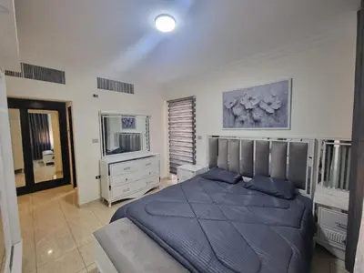 a bedroom with a blue bed and a television at Dier Ghbar 2 bedrooms-A in Amman