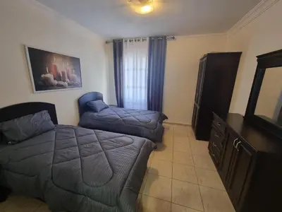 a bedroom with a bed and a chair and a dresser at Dier Ghbar 2 bedrooms-A in Amman