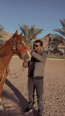 a man standing next to a brown horse at Camp star road safari in Wadi Rum
