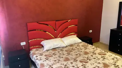 a bedroom with a bed with a red headboard at Izz AlDin Tamimi St شقة مفروش سوبر ديلوكس الجبيهة in Ţāb Kirā‘