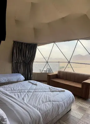 a bedroom with a bed and a couch and a large window at Bright Stars Camp in Disah