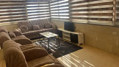 a waiting room with couches and a table and windows at الروف سوبر ديلوكس 2 غرف نوم صالة جلوس و طعام مكيفة للإيجار in Amman