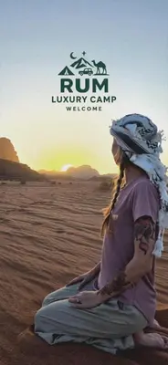 a woman sitting on the sand in the desert at RUM LUXURY CAMp in Wadi Rum