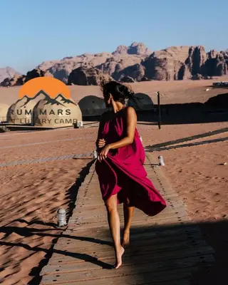 a woman in a dress walking in the desert at RUM MARS lUXURY CAMP in Wadi Rum