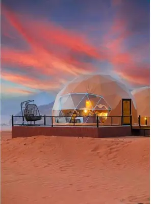 a large domed building in the desert with a sunset at RUM MARS lUXURY CAMP in Wadi Rum