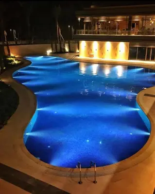 a swimming pool lit up with blue lights at night at Alraha village-aqaba قرية الراحة- مرسى زايد -العقبة in Aqaba