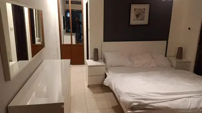 a bedroom with a white bed and a large mirror at Elegant Apartment in Amman