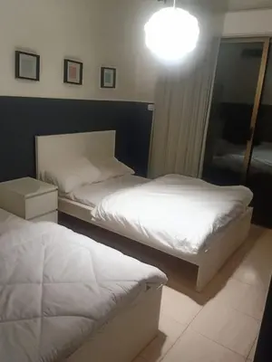 a bedroom with two beds and a light on the wall at Elegant Apartment in Amman