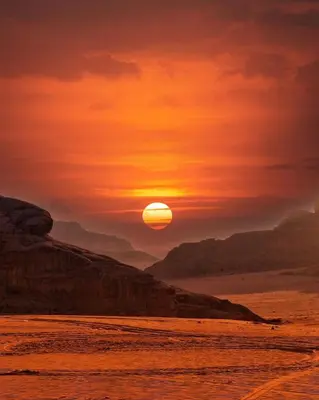 a sunset on the beach with the sun setting at Wadi Rum Bedouin Story Camp & Tours in Wadi Rum