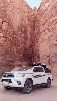 a white suv parked in front of a canyon at Dream Bedouin Life Camp Wadi Rum in Disah