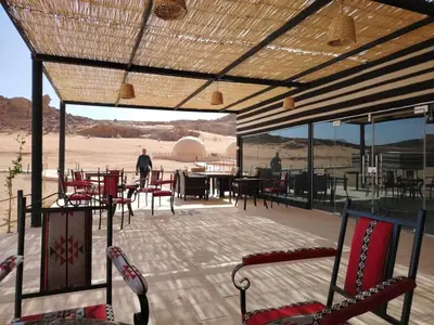 a patio with chairs and tables and a view of the desert at Eagle Rum Camp in Disah