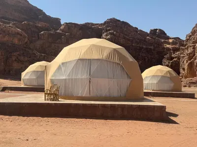 two tents in the desert with mountains in the background at rum luxury camp in Wadi Rum