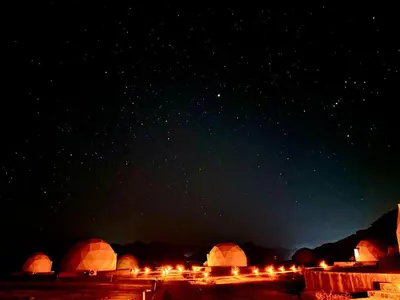 a group of domed buildings with lights in the night at Rum Moon Camp in Wadi Rum