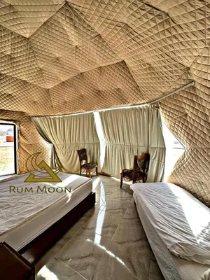 a room with two beds and two chairs in it at Rum Moon Camp in Wadi Rum