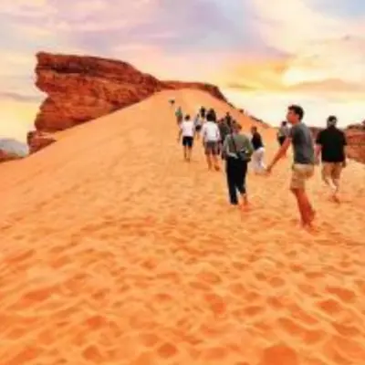 a group of people walking down a sand hill at Rum Moon Camp in Wadi Rum