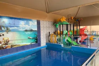 a swimming pool with a water slide in front of a mural at شقه سياحيه أبو نصير in Ţāb Kirā‘