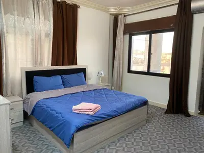 a bedroom with a bed with blue sheets and a window at Jerash Gate in Jerash