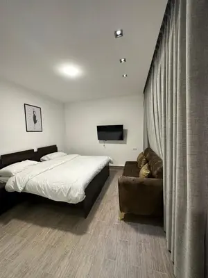 a bedroom with a bed and a couch and a television at central apartment for rent 16 in Umm Uthainah