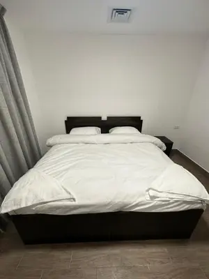 a bedroom with a large bed with white sheets at central apartment for rent 17 in Amman