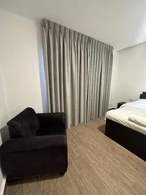 a bedroom with a chair next to a bed at central apartment for rent 18 in Umm Uthainah