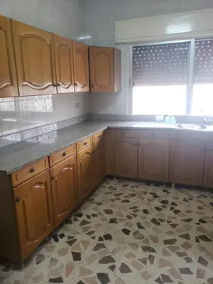 an empty kitchen with wooden cabinets and a window at Alotaibi #6 in Amman