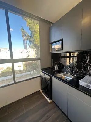 a kitchen with a stove and a sink and a window at central apartment for rent 20 in Amman