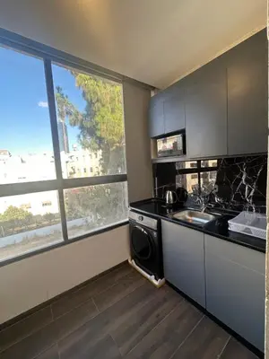 a kitchen with a stove and a sink and a window at central apartment for rent 20 in Amman