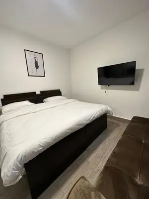 a bedroom with a large bed and a flat screen tv at central apartment for rent 23 in Umm Uthainah