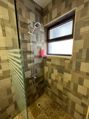 a bathroom with a glass shower with a window at 10 Antica jabalal-lwebdeh in Amman