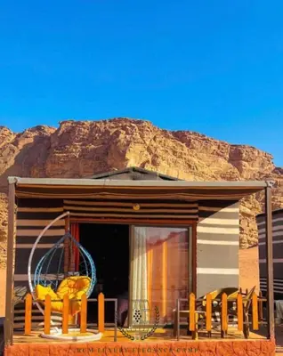 a house with a balcony with a mountain in the background at RUM lUXURY ELEGANCE CAMP in Wadi Rum