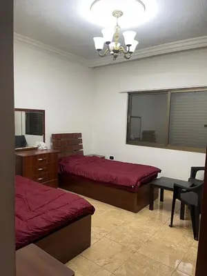 a bedroom with two beds and a table and a chandelier at Samar Home in Amman