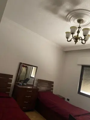 a bedroom with two beds and a mirror and a chandelier at Samar Home in Amman