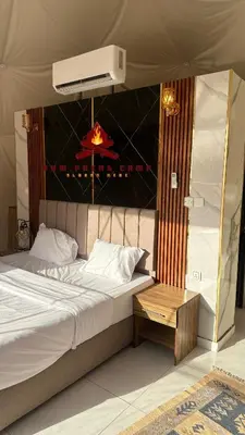 a bed in a tent with a table next to it at Rum prens camp in Wadi Rum