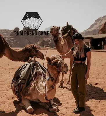 a woman standing next to a camel in the desert at Rum prens camp in Wadi Rum