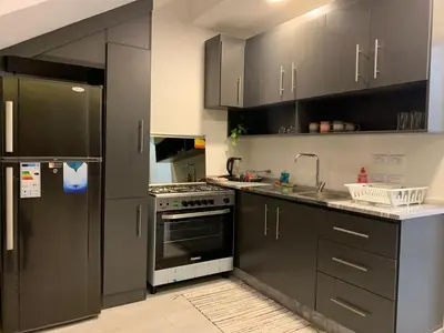 a kitchen with black cabinets and a sink and a stove at Rosario Farm Home in Amman