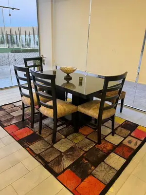 a dining room table and chairs on a rug at Rosario Farm Home in Amman