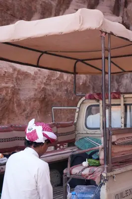 a man standing in front of a truck with a bed at Bedouin cave wadi rum campsite in Wadi Rum